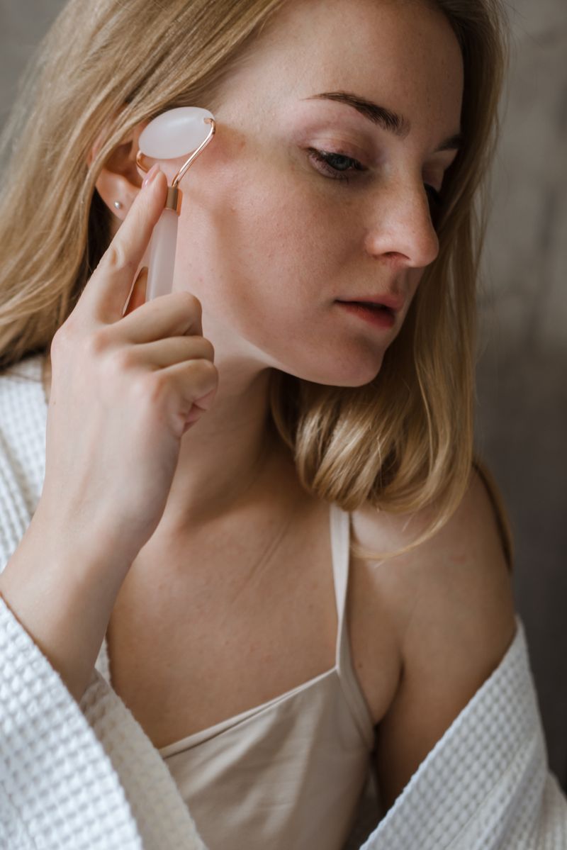 Mujer masajeando su rostro con rodillo facial