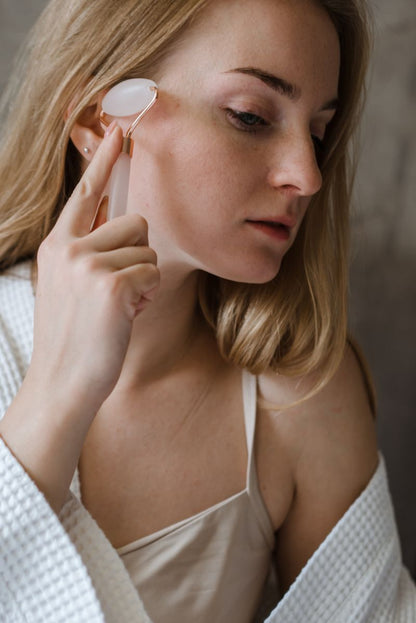 Mujer masajeando su rostro con rodillo facial