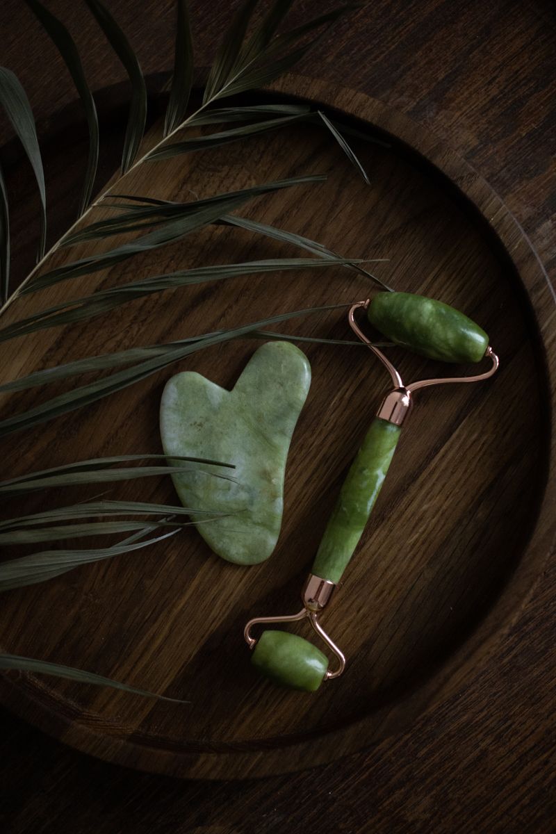 Gua sha y jade roller sobre superficie de madera
