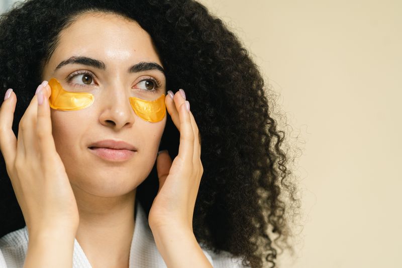 Mujer aplicando parches bajo los ojos rutina de cuidado